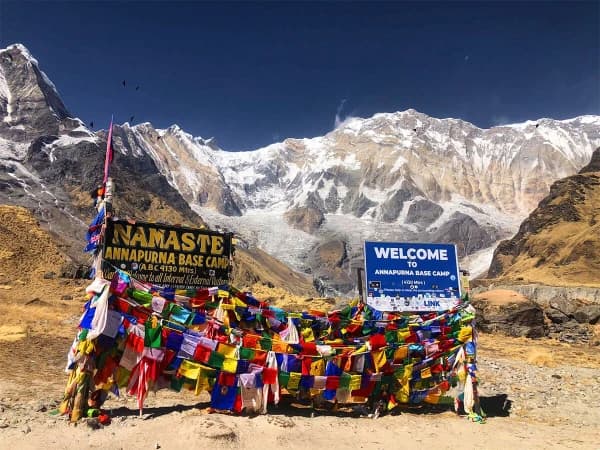 Sunrise View Of The Annapurna Base Camp With Welcome Sign And Flags